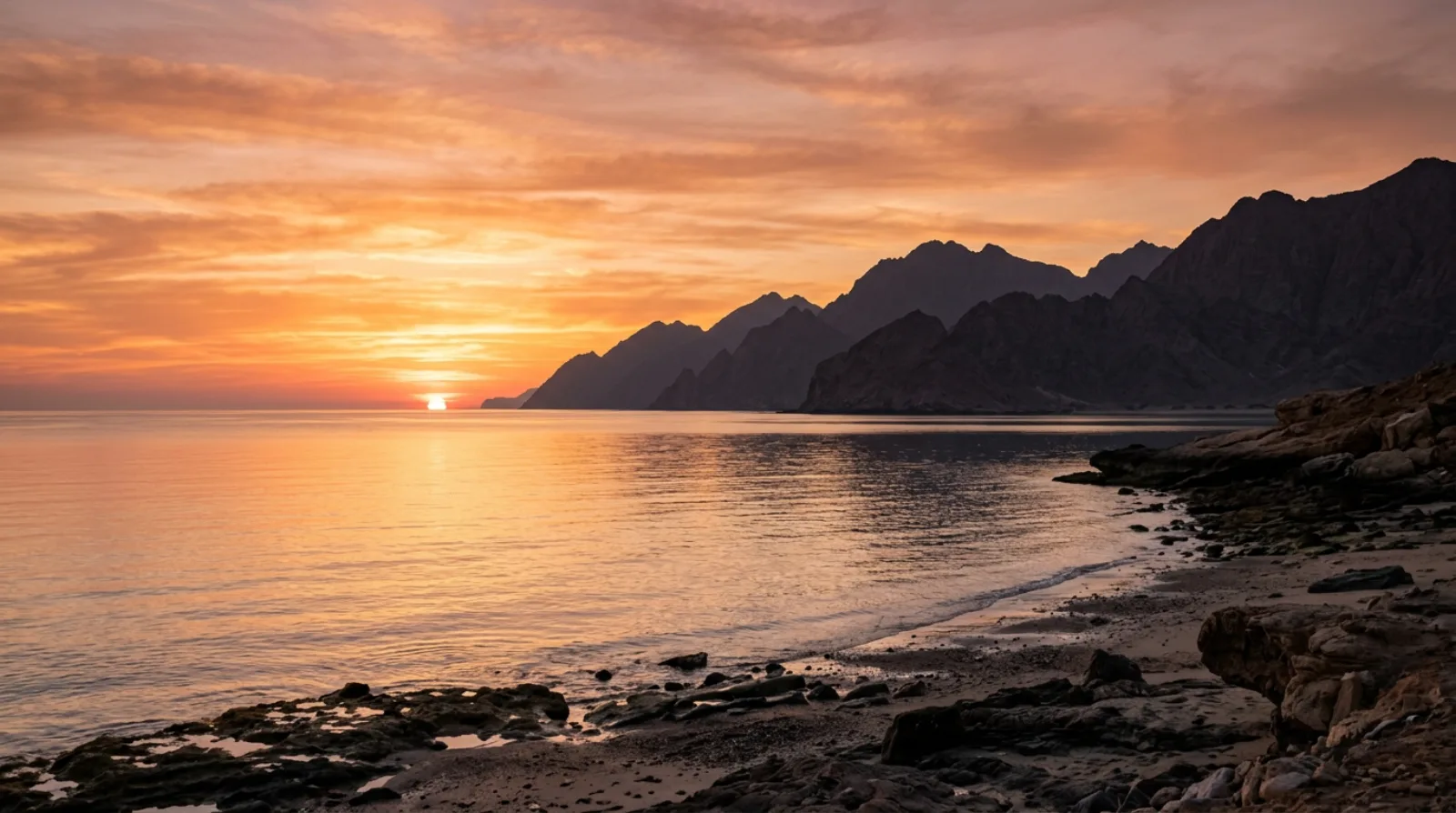 Sunrise over the Gulf of Oman with Hajar Mountain silhouettes and golden sky